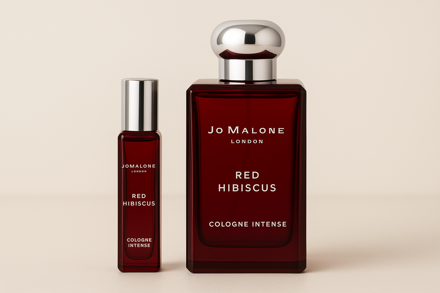 Jo Malone Red Hibiscus Cologne Intense 12 ml prøve som står ved siden av 100 ml parfymeflaske med Jo Malone Red Hibiscus Cologne Intense som har hvit skrift på mørkerød flaske