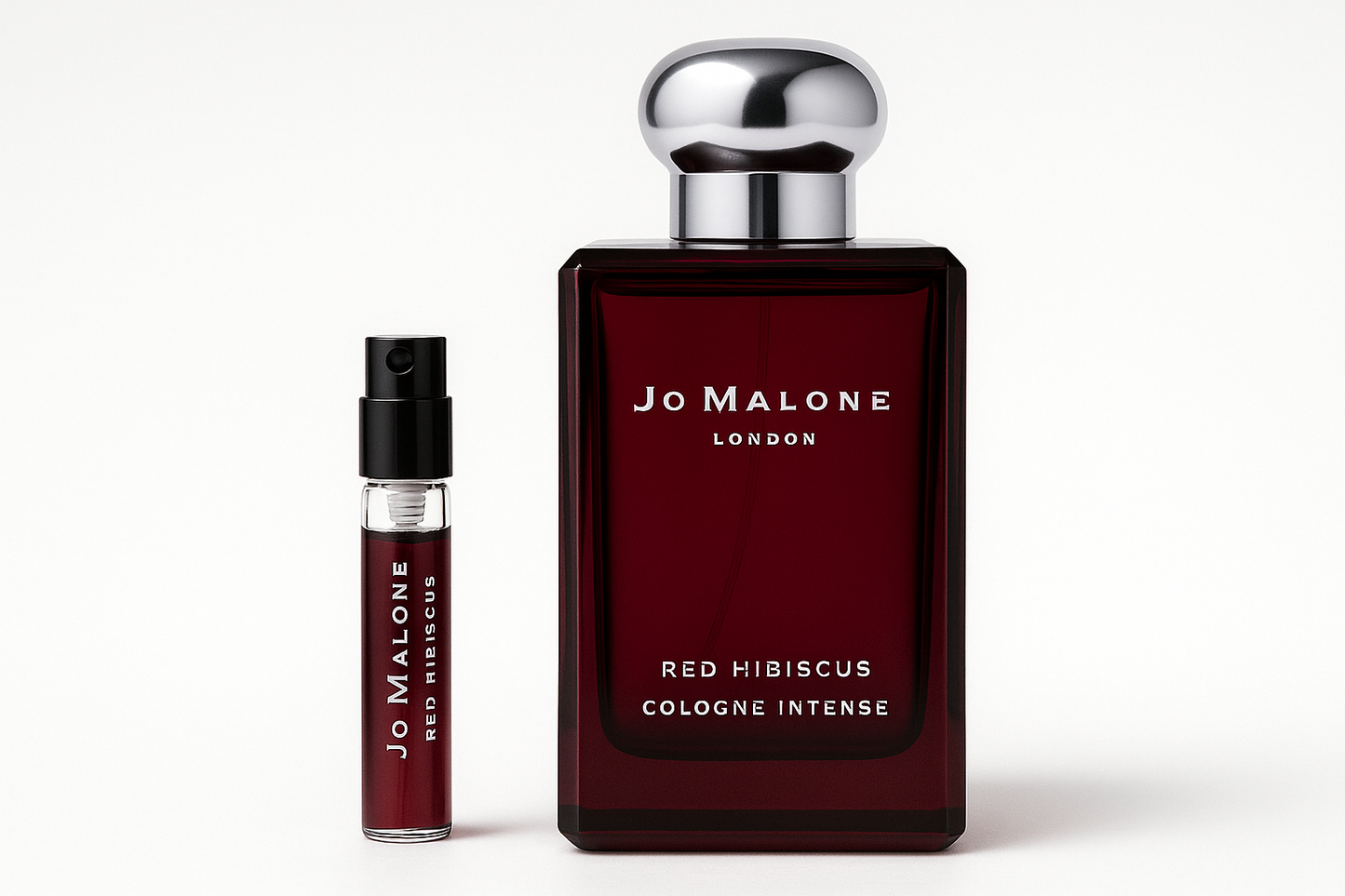 Jo Malone Red Hibiscus Cologne Intense 2 ml prøve som står ved siden av 100 ml parfymeflaske med Jo Malone Red Hibiscus Cologne Intense som har hvit skrift på mørkerød flaske